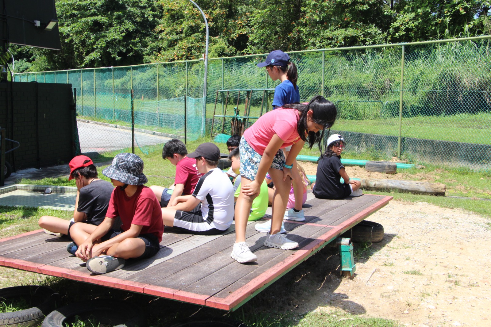 Children resting on a wooden platform during an outdoor camp activity