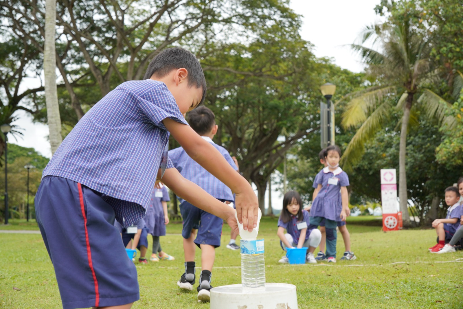 Boy playing a water relay game on the field at holiday camp